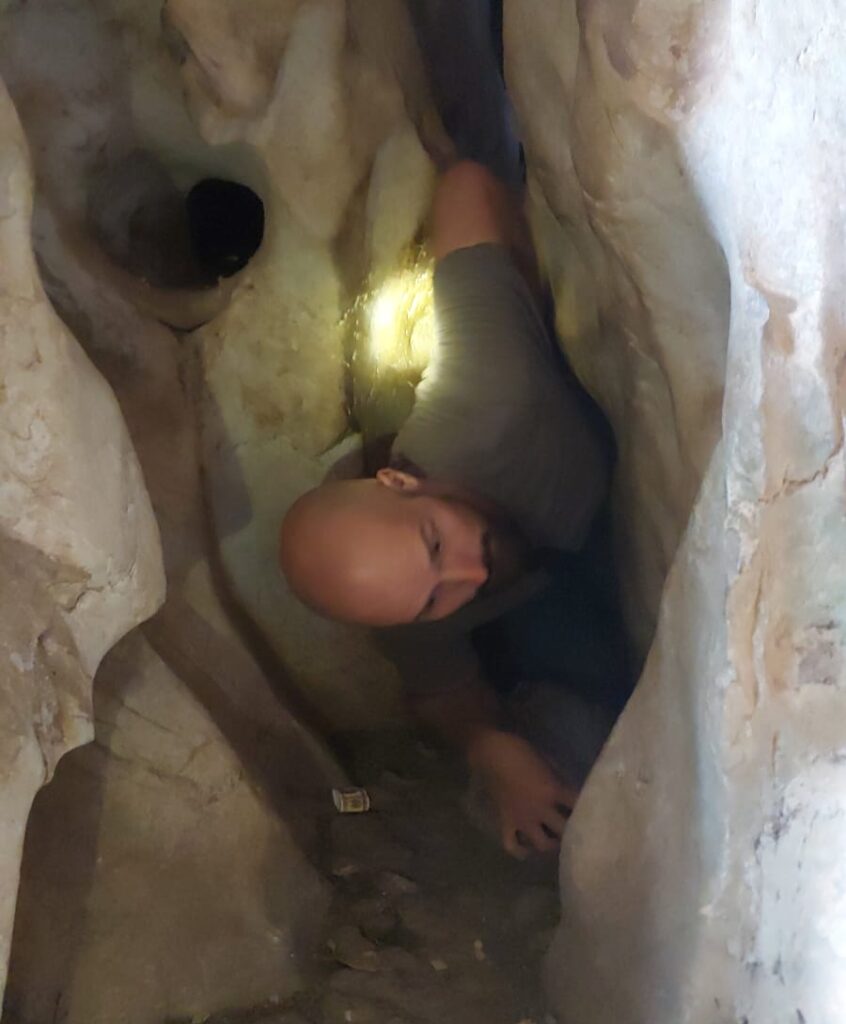 Me squeezing through a tiny crack in a cave.