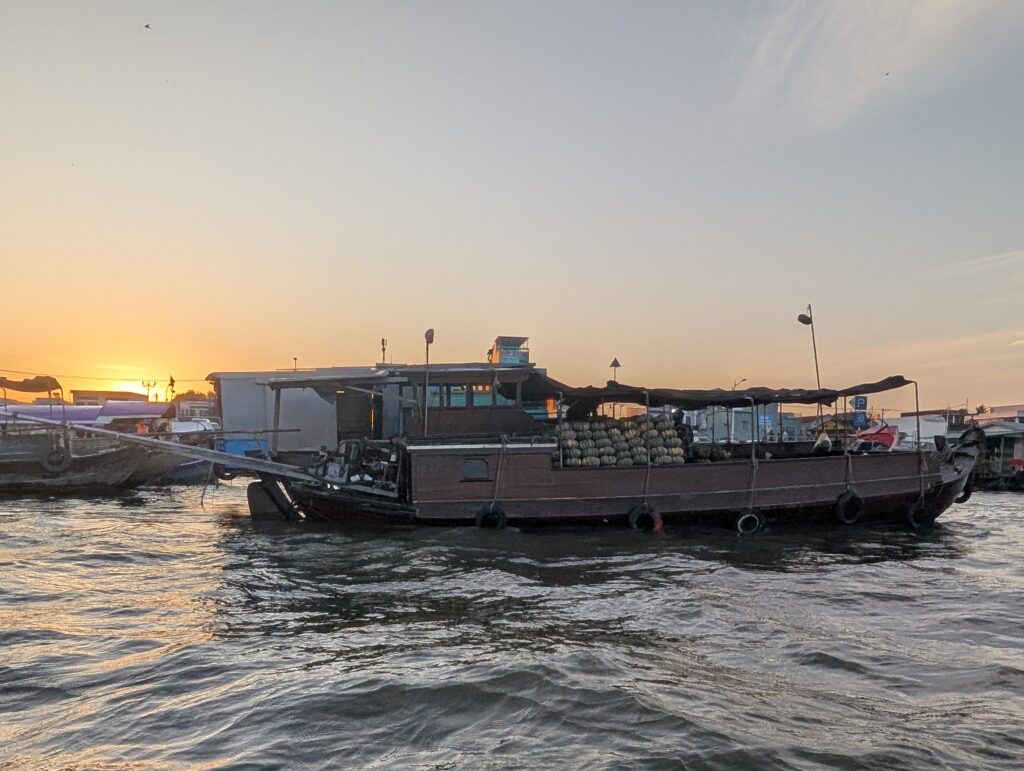 A Big barge on the river in Can Tho, piled with pumpkins, with sunrising in the background.