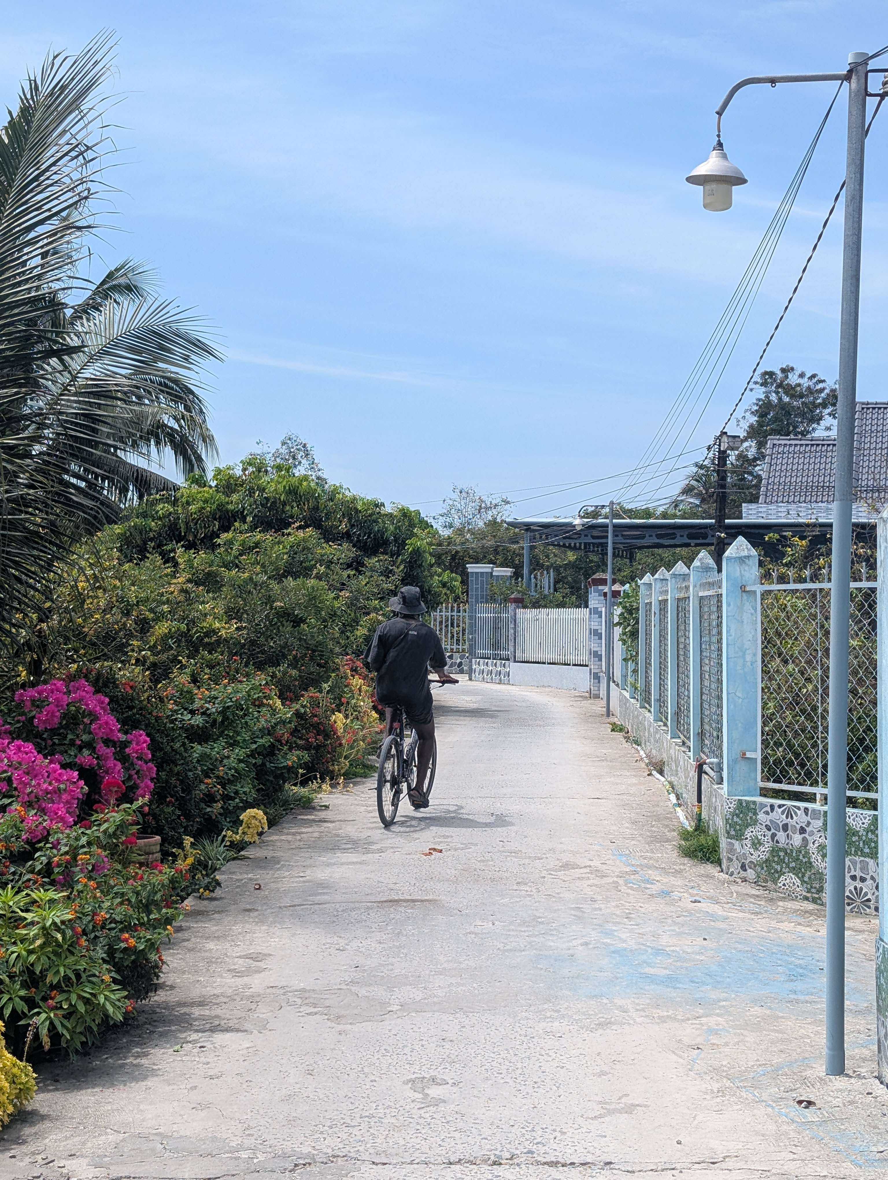 Mary-Ann riding a bike along a street on An Binh island.