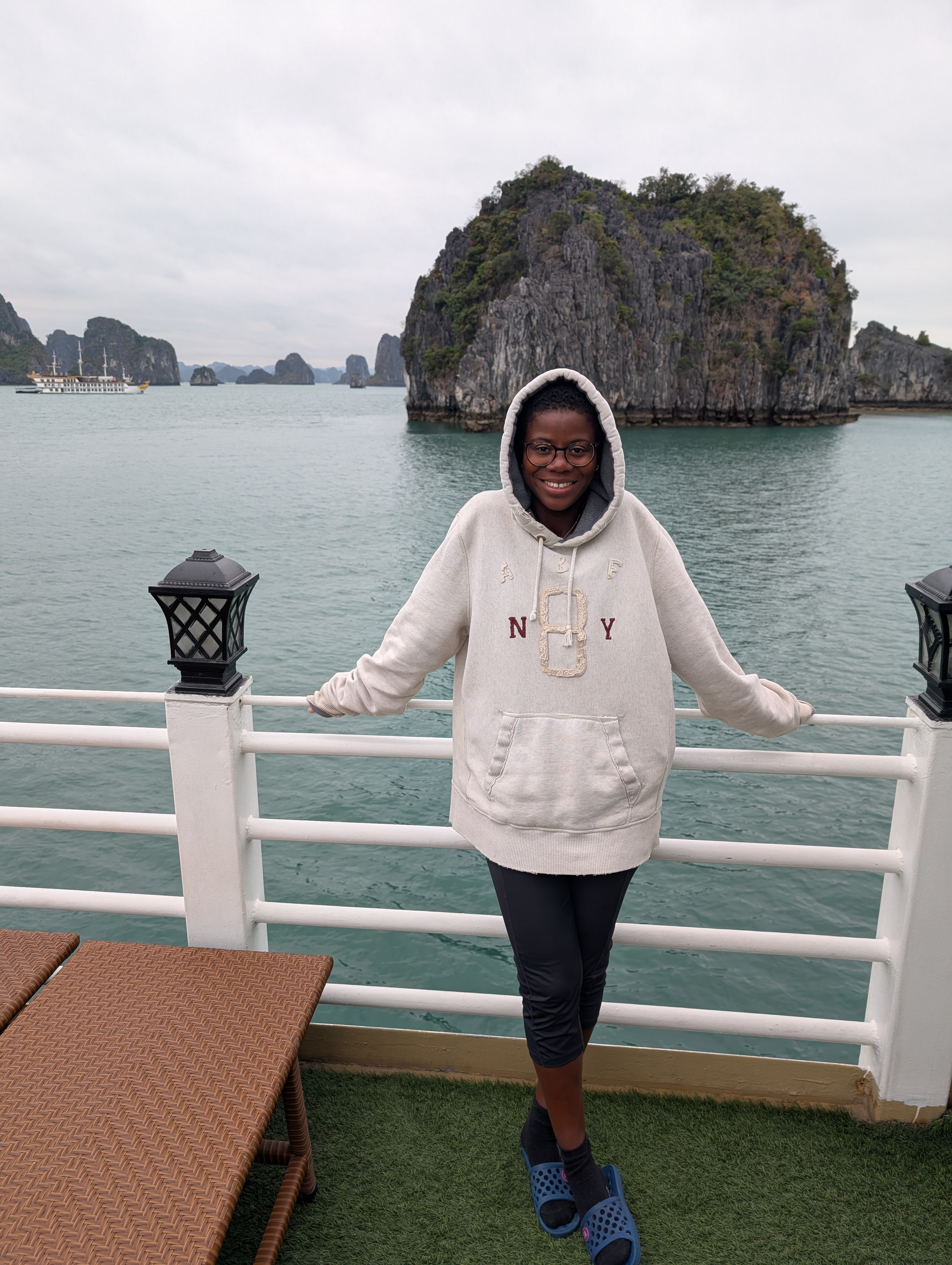 Mary-Ann standing on the cruise boat in Bai Tu Long bay, with the Lime stone karsts in the background.