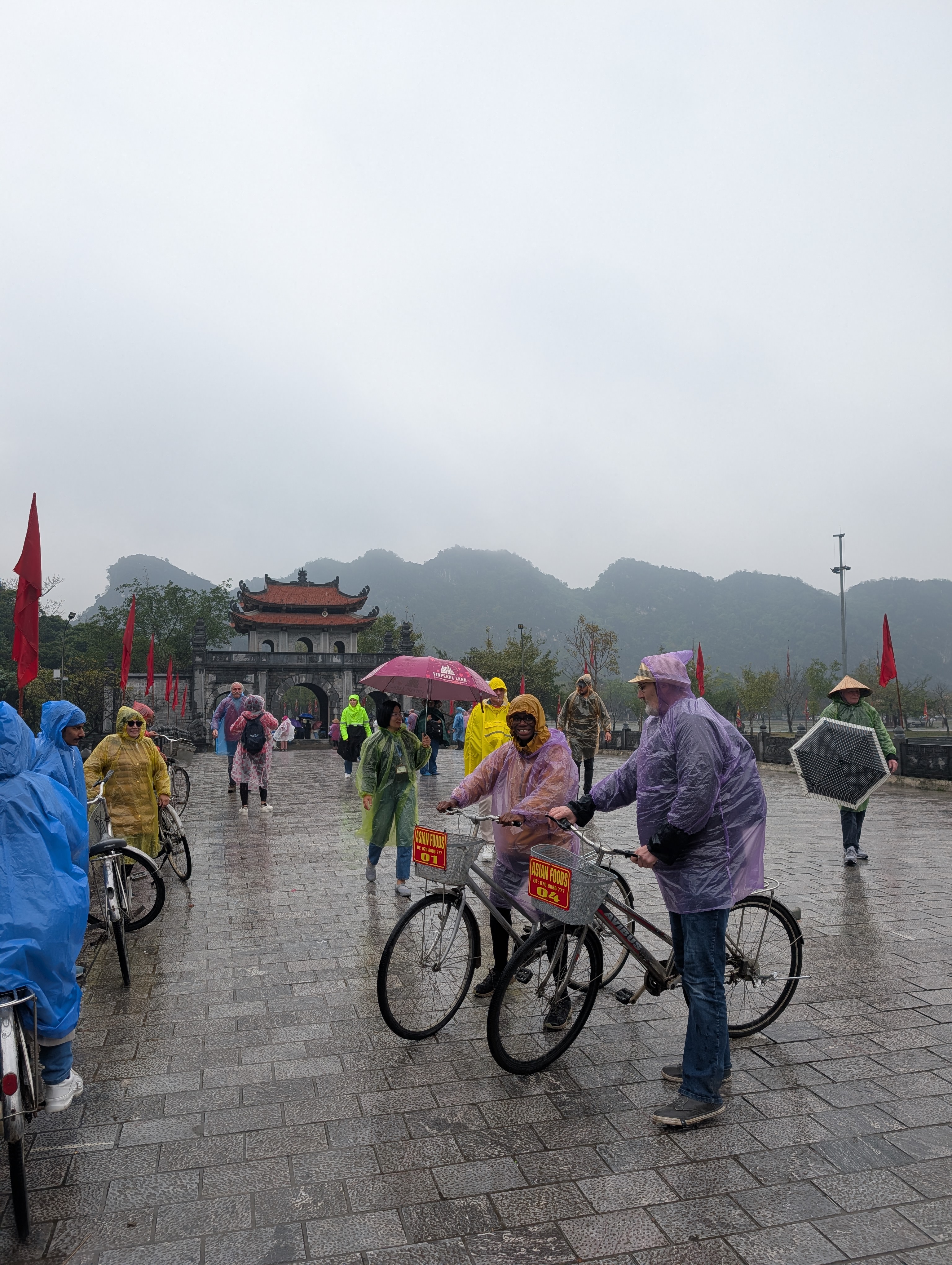 My Dad and Mary-Ann on bikes int he rain, with some of Ninh Binhs mountains in the background.