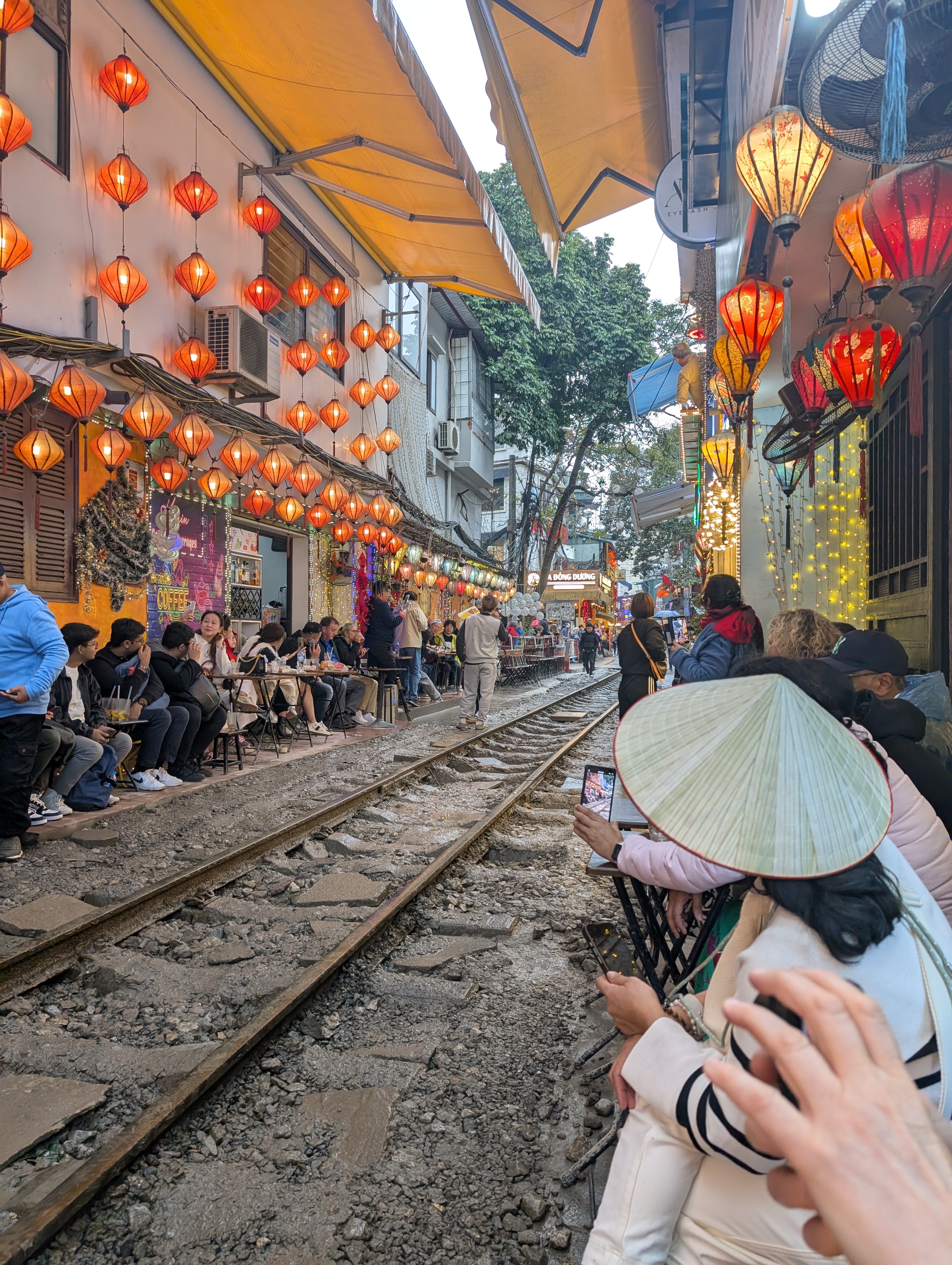 Lantern filled train street in Hanoi with people waiting for the train to come.