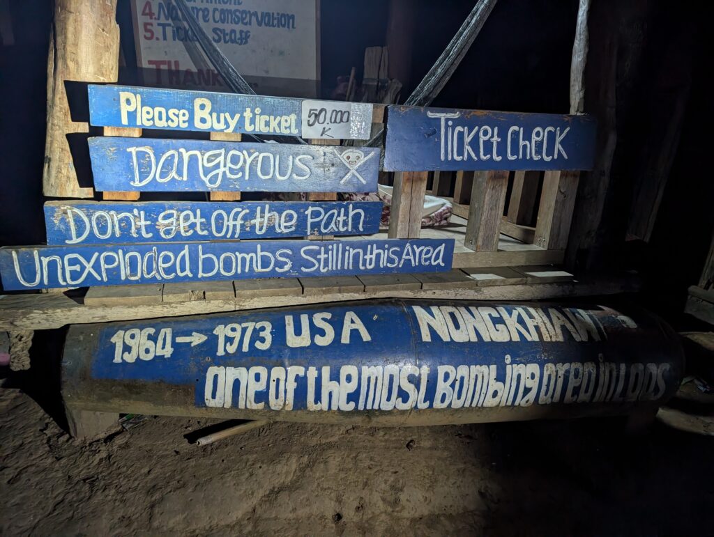 A hand painted sign warning hikers of unexploded bombs in the area.