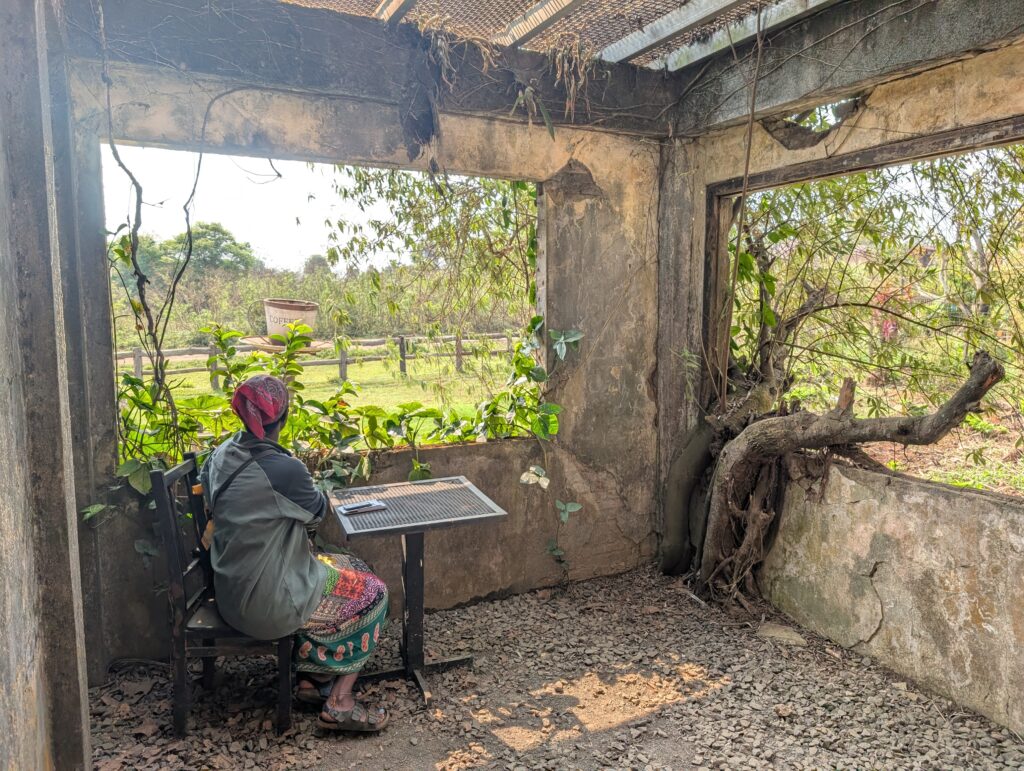 Mary-Ann sitting at a table inside the 1971 cafe, with roots growing through the walls!