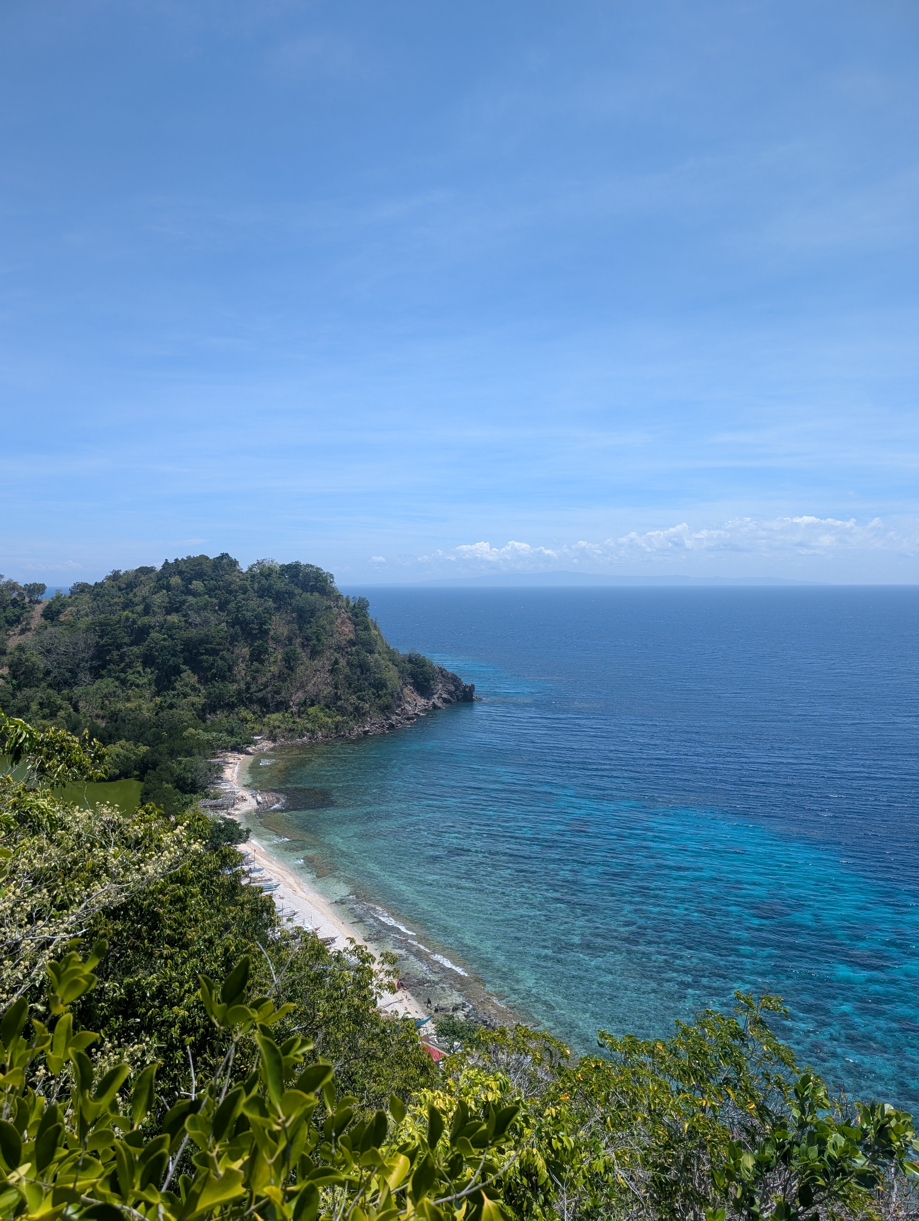 Another viewpoint on Apo island, this time across a bay with a white sand beach and crystal clear blue waters.