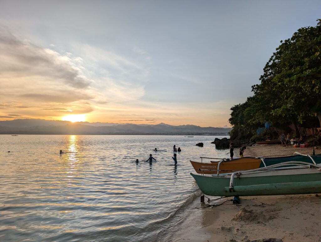 An evening sunset picture of a bech in Anda, with locals enjoying the water!