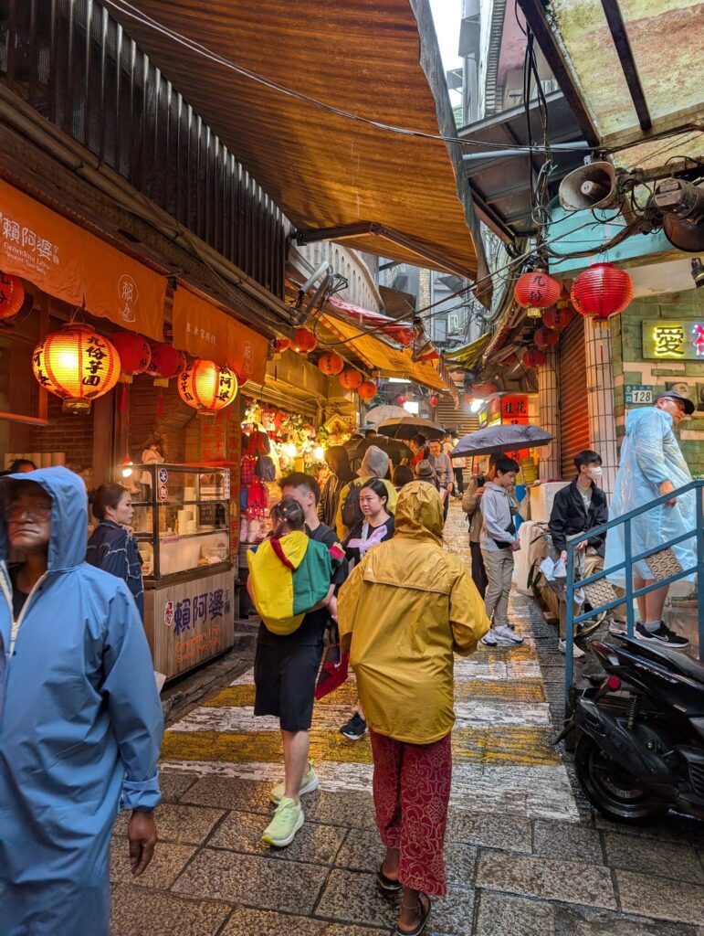 Mary-Ann walking through the beautiful Jiufen old street, in a raincoat.