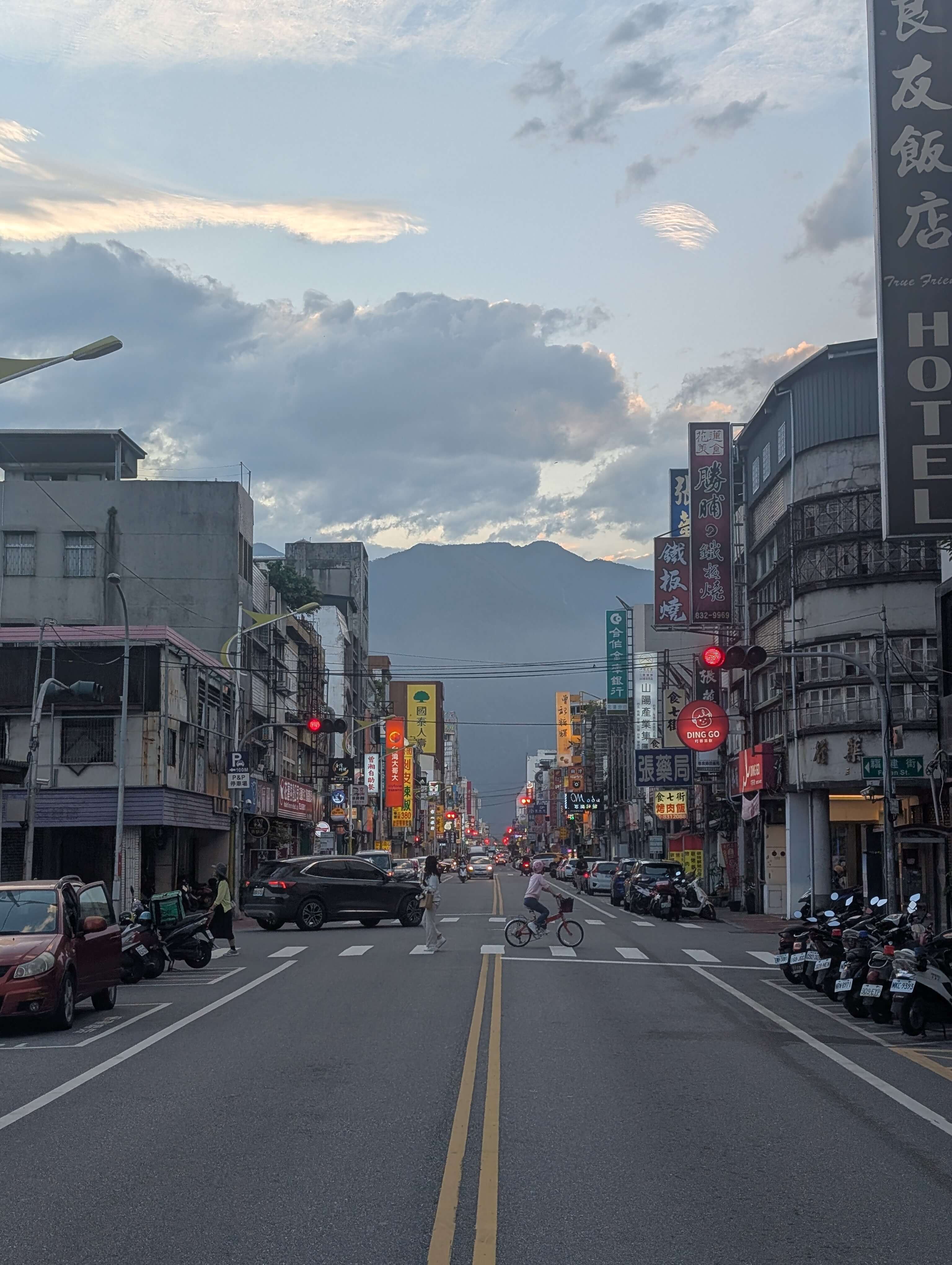 A shot looking down a Taiwanese city road, adorned with proper road markings and smooth tarmac. There is also a beautiful mountain in the background.