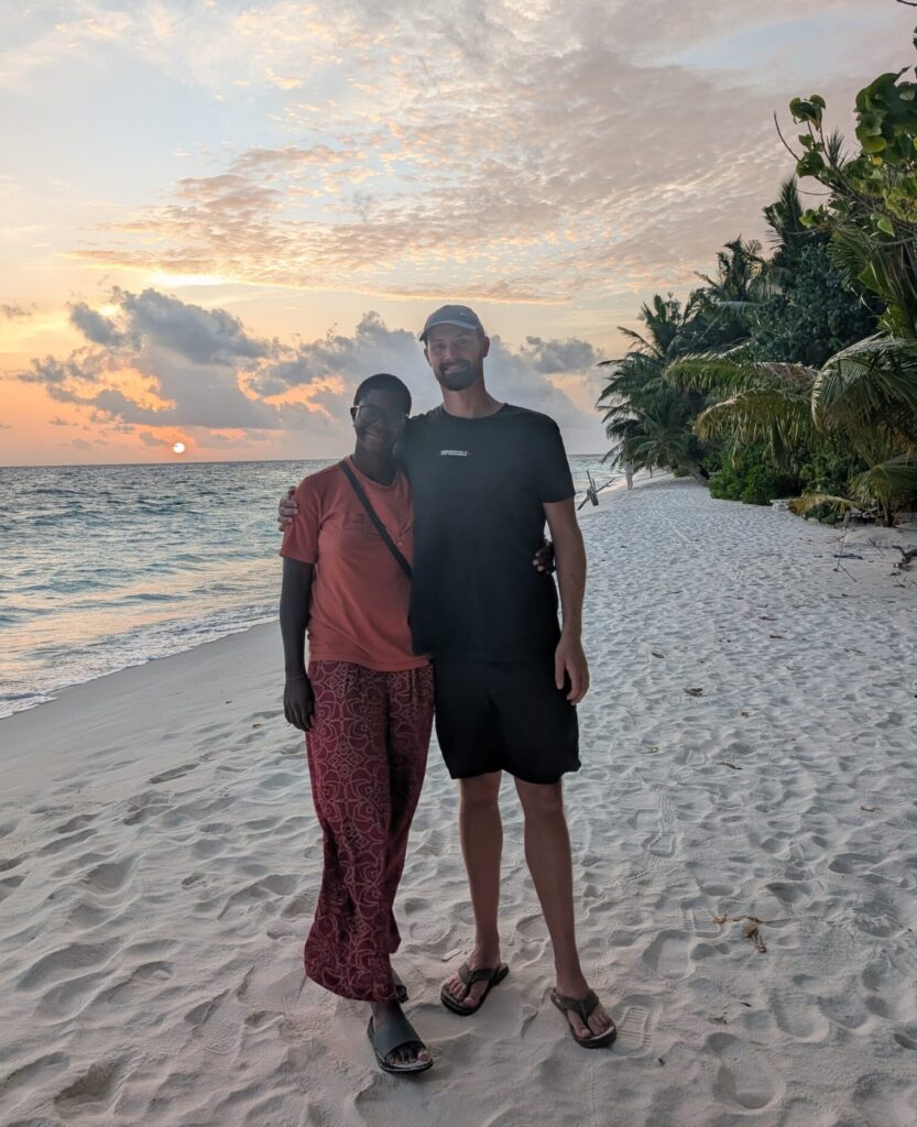 MAry-Ann and I standing together on a beach with a sunset in the background.